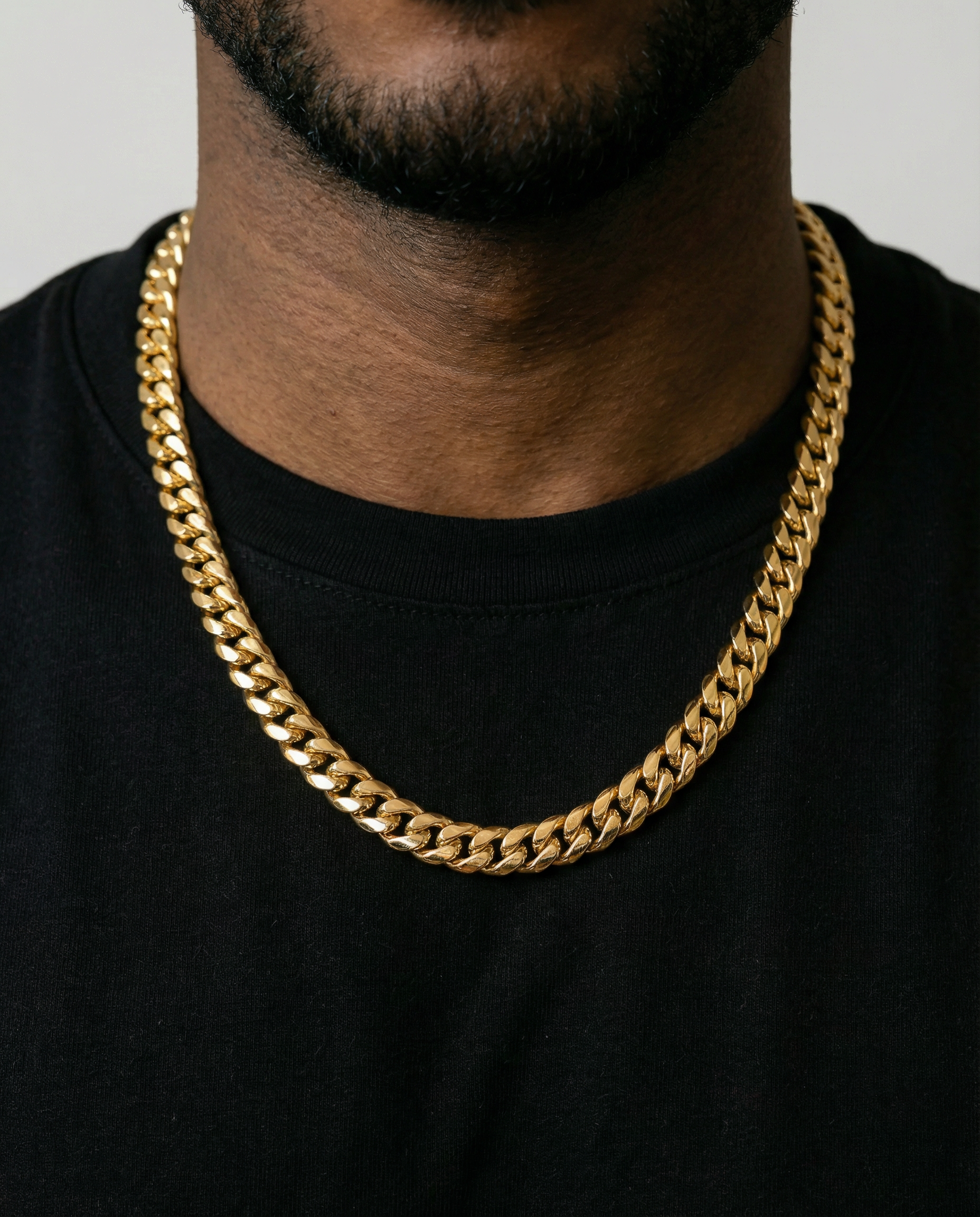Close up shot of man wearing a yellow gold cuban link chain