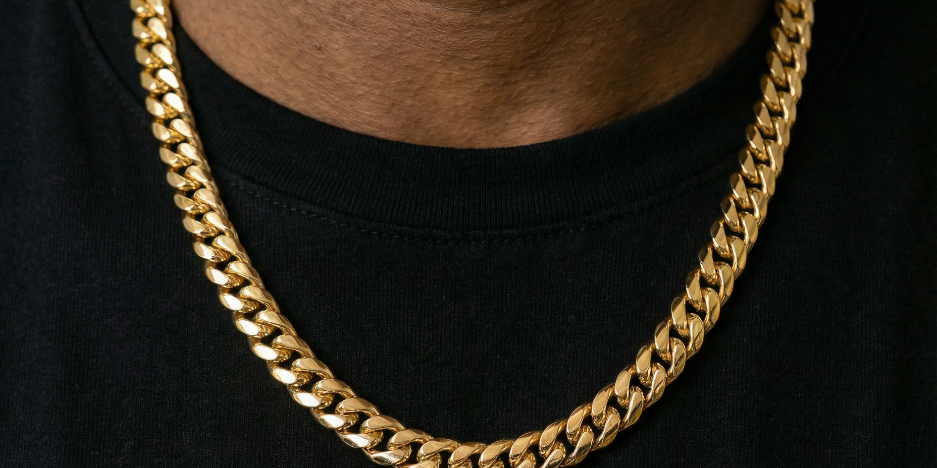 Close up shot of man wearing a yellow gold cuban link chain